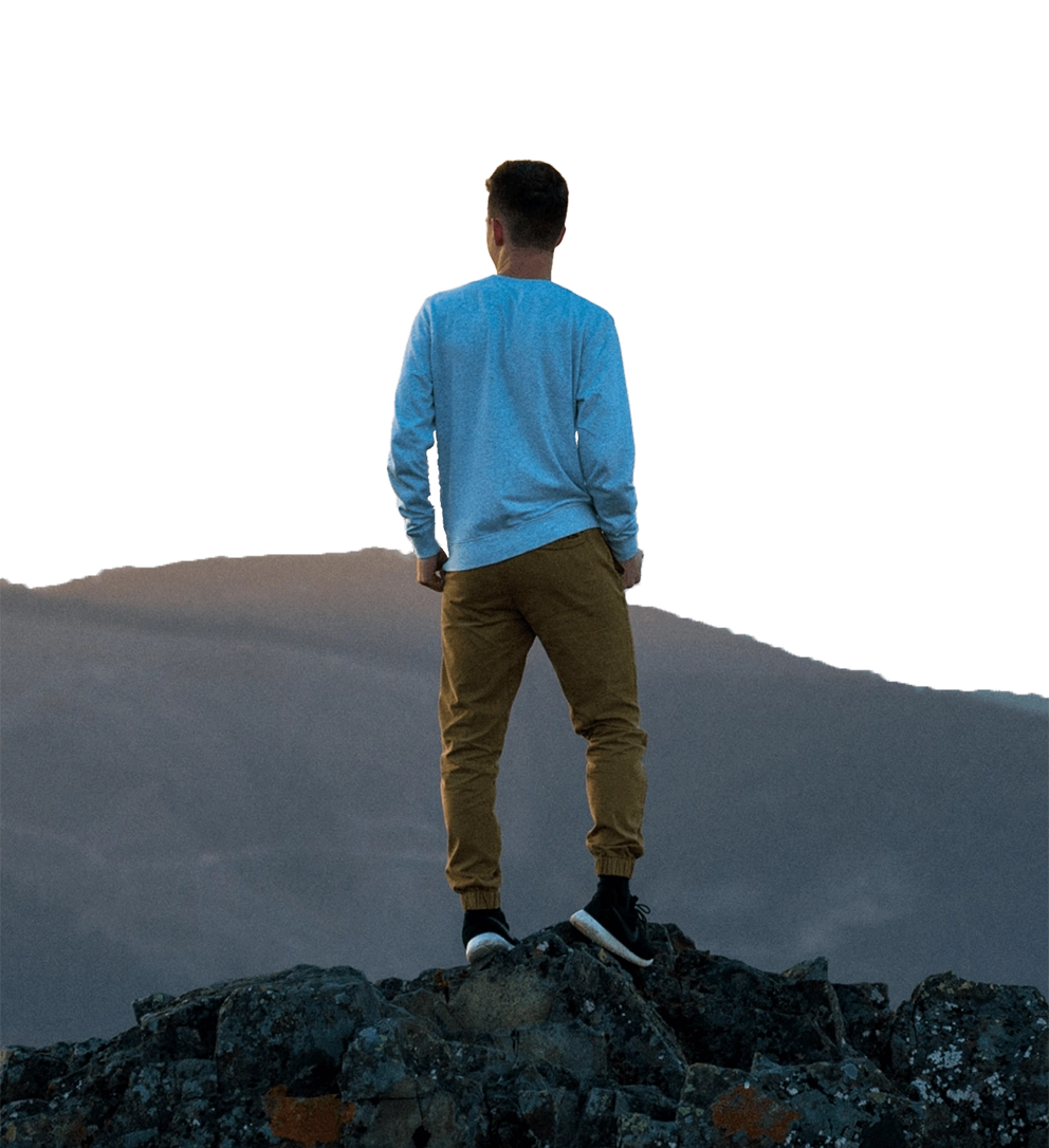 Person standing at peak of rocks overlooking mountains